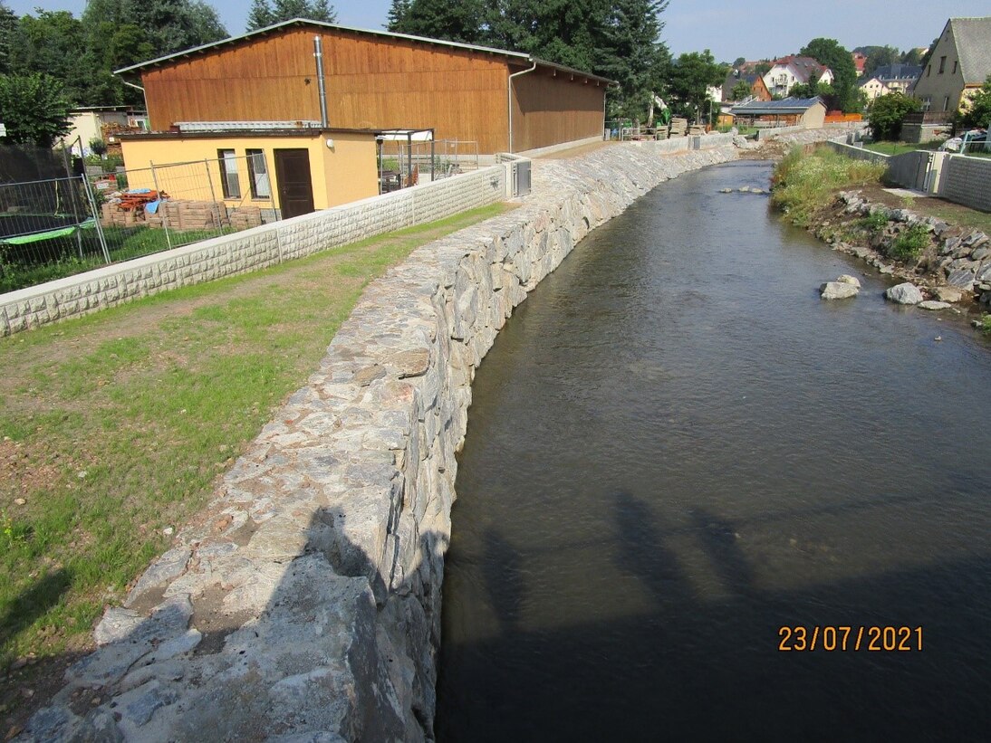 Blick auf Fluss mit steinerner Mauer