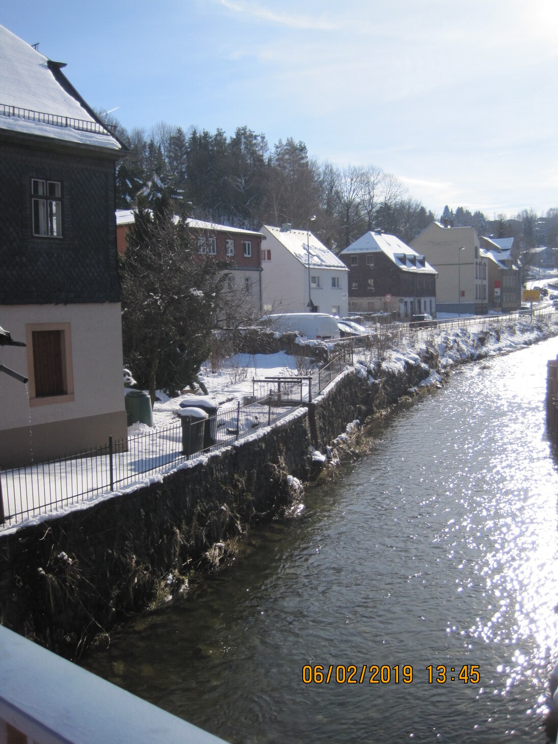 Blick auf Fluss mit angrenzenden Häusern, die schneebedeckt sind