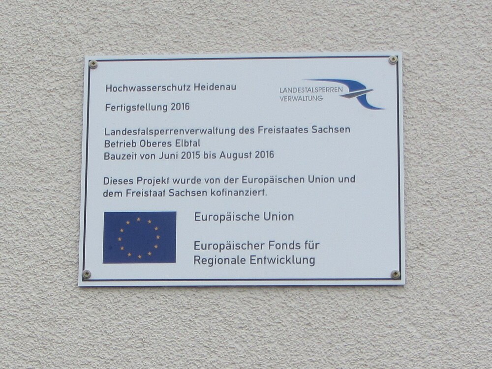 Informationsschild über die EU-Förderung auf einer Mauer