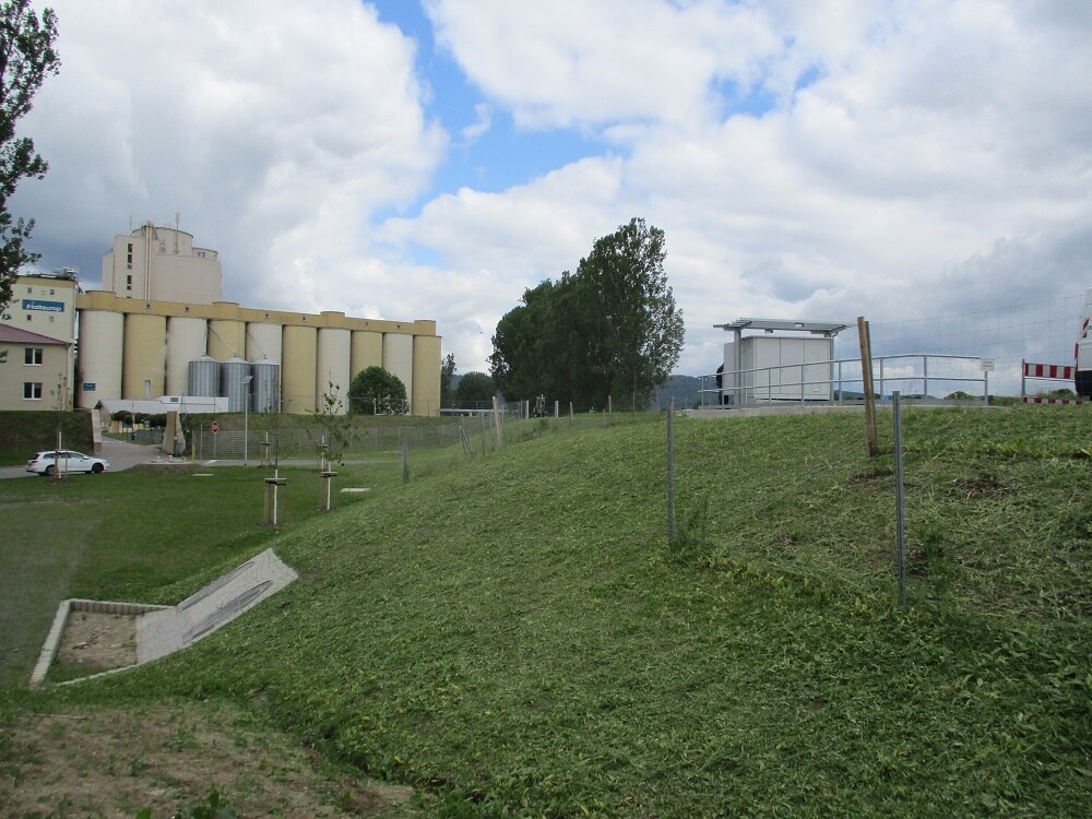 Fabrikgelände aus anderer Perspektive mit viel Wiese und dem Gebäude im Hintergrund