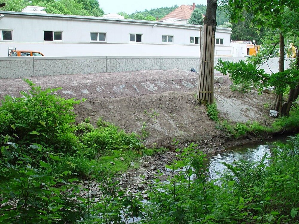 Gebäude mit Mauer an Uferböschung eines Flusses