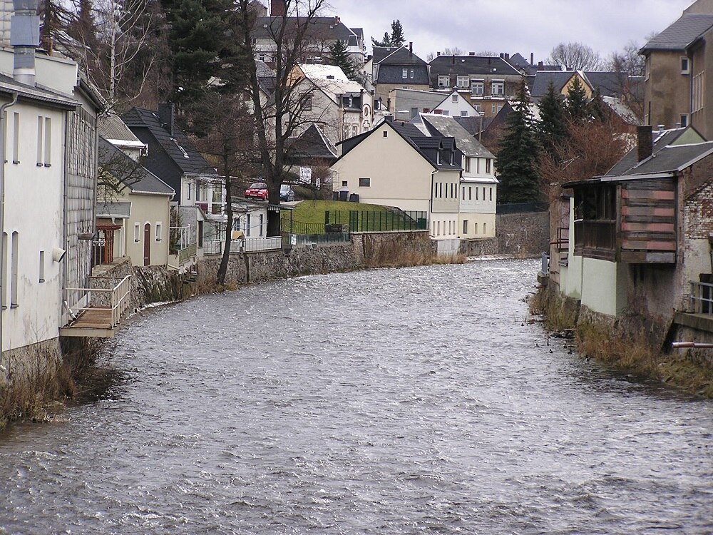 Ein breiter Fluss der zwischen direkt angrenzenden Häusern fließt