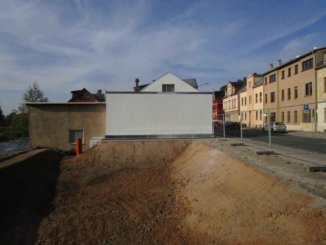 Blick auf Erdgrube und daneben neue Wand eines Hauses