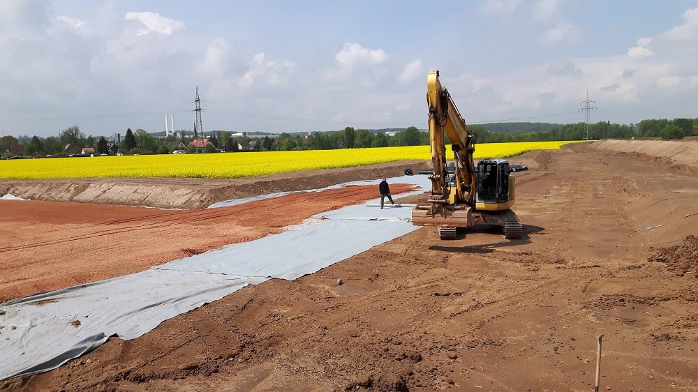 Baustelle mit Bagger und gelbes Rapsfeld im Hintergrund