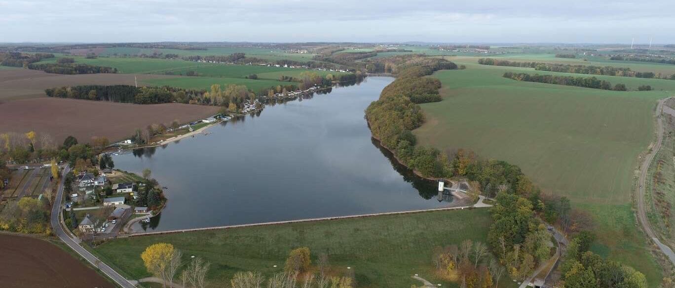 Luftbild eines Sees mit Campingplatz und Feldern drumherum