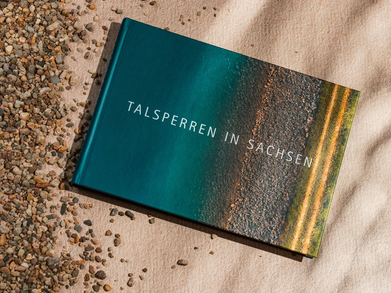 Das Bild zeigt das Buch Talsperren in Sachsen, das im Sand liegt