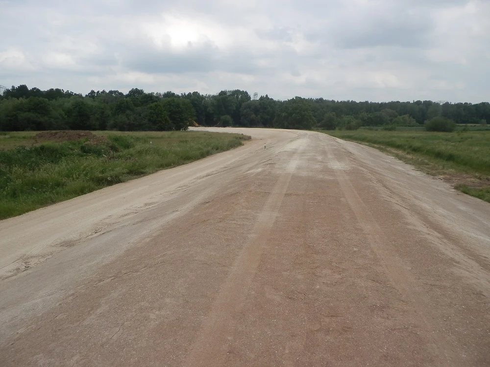 breite Straße aus Erde durch Grünflächen