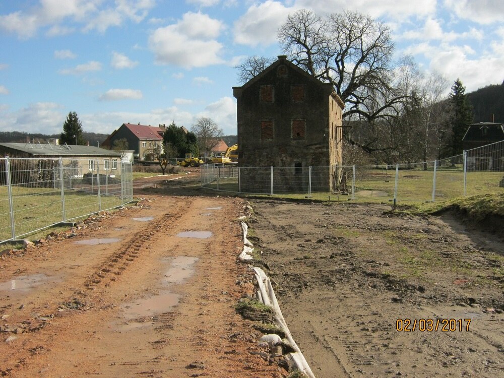 Blick auf altes eingezäuntes Haus mit erdigem Weg dazwischen