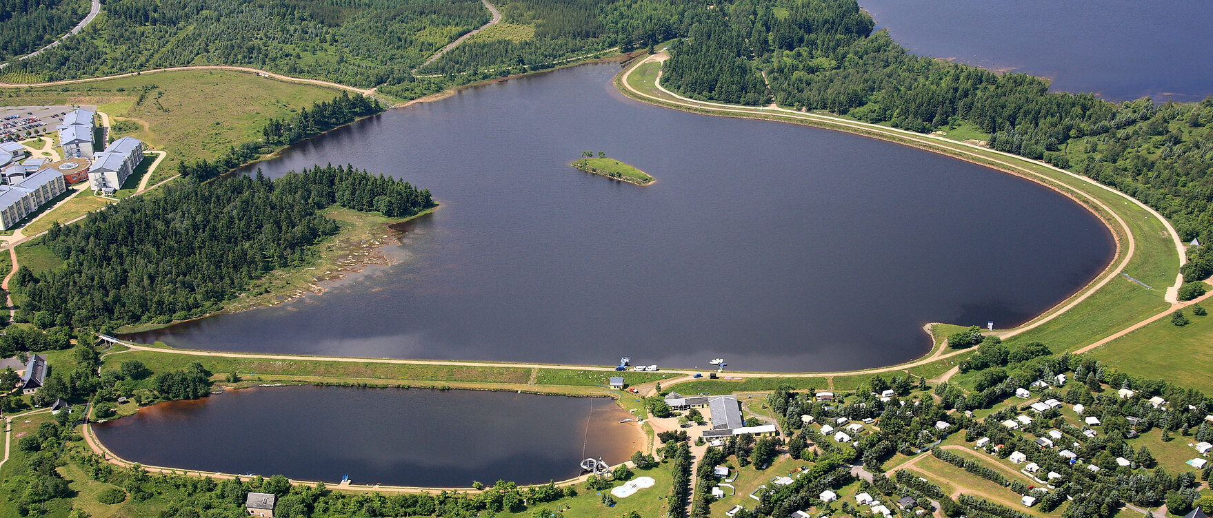 Luftbild dreier nebeneinander liegender Seen. Im Vordergrund ein Campingplatz und rings um die Seen viel Grün.