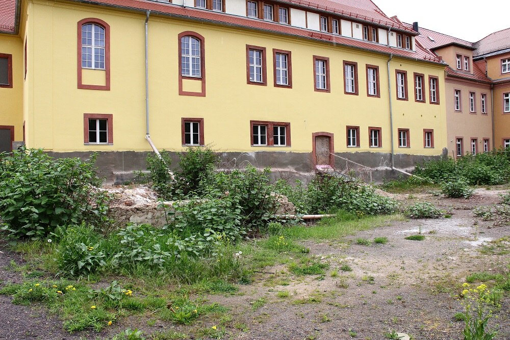 Blick auf ein langes gelbes Haus mit roten Rahmen um die Fenster