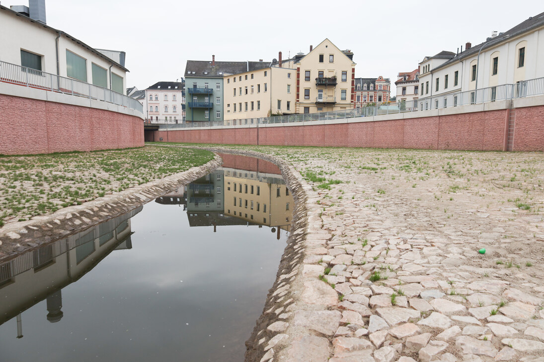 Blick auf einen Fluss, eingebettet zwischen gepflasterte Flächen und Mauern