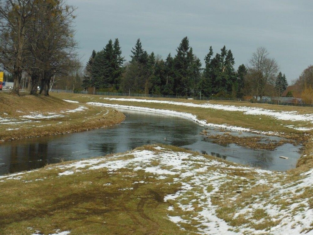 Fluss, die Wiesen am Ufer sind leicht schneebedeckt