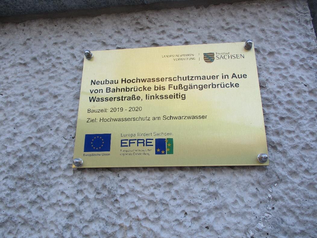 eine kleine goldene Metalltafel mit EU-Logo, angebracht auf einer Mauer