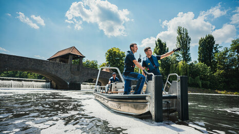 zwei Männer stehen in einem Bollt auf dem Wasser und schauen gemeinsam in eine Richtung