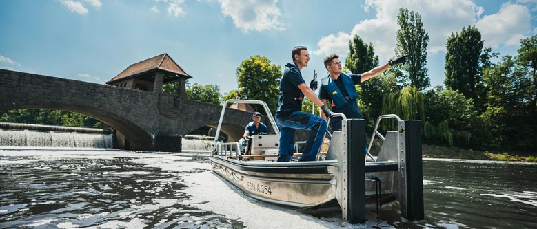 zwei Männer stehen in einem Bollt auf dem Wasser und schauen gemeinsam in eine Richtung