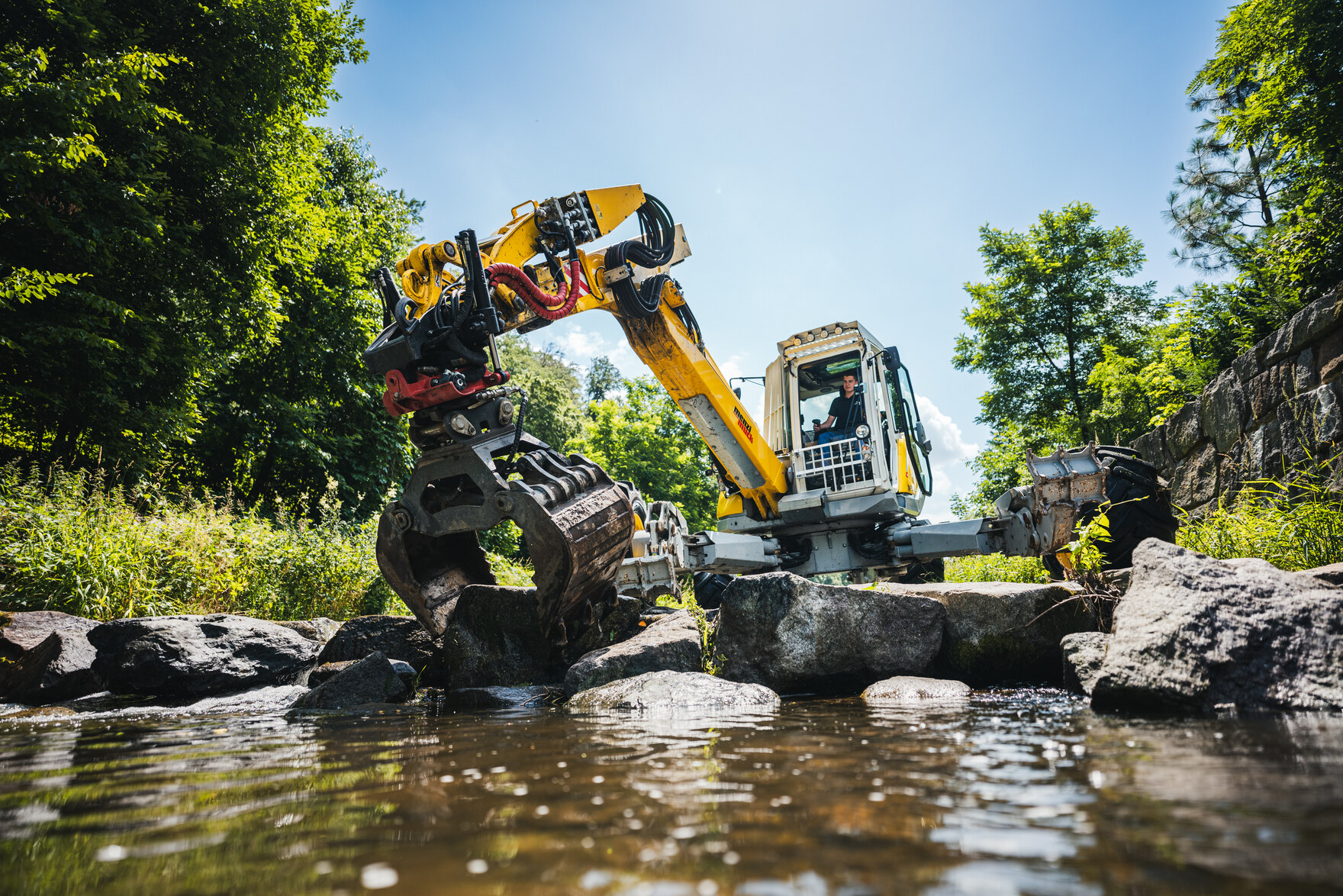 gelber Bagger, der große Steine bearbeitet