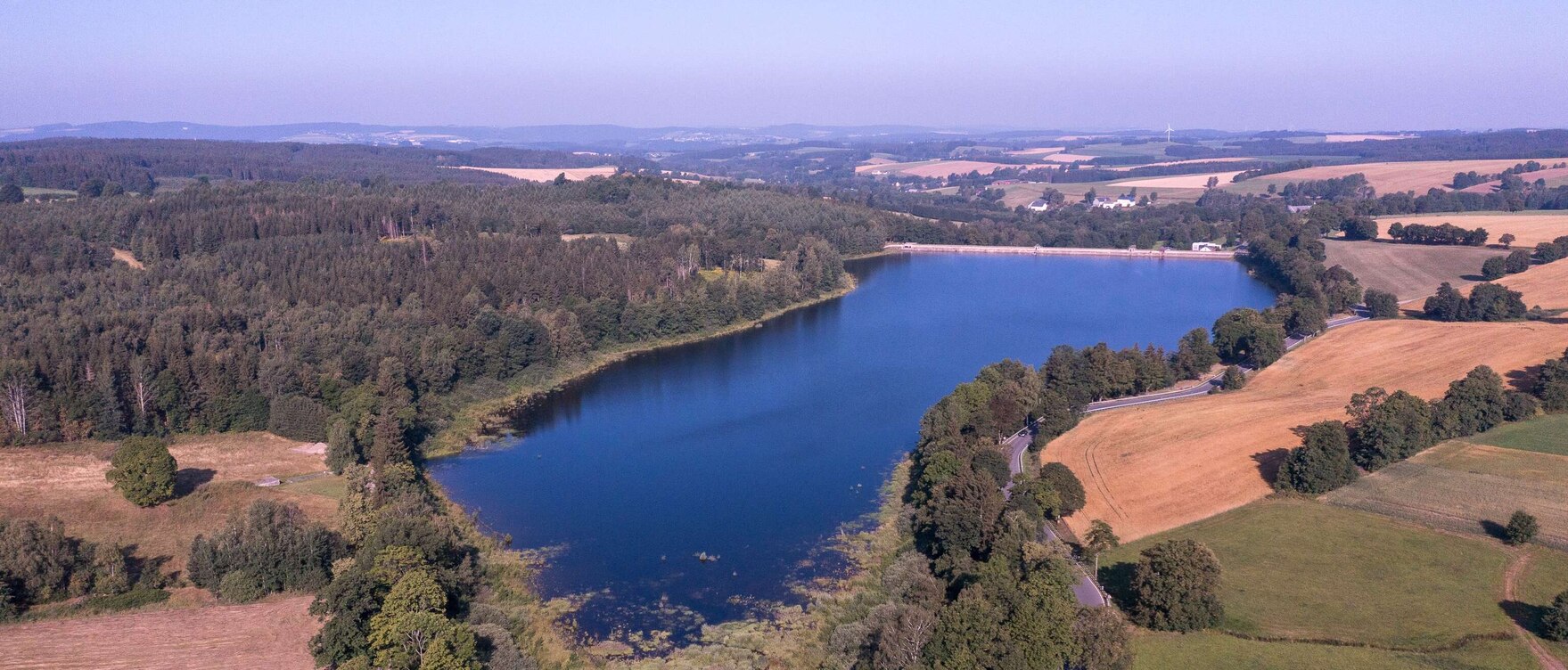 Luftbild eines Sees umgeben von Bäumen und Feldern