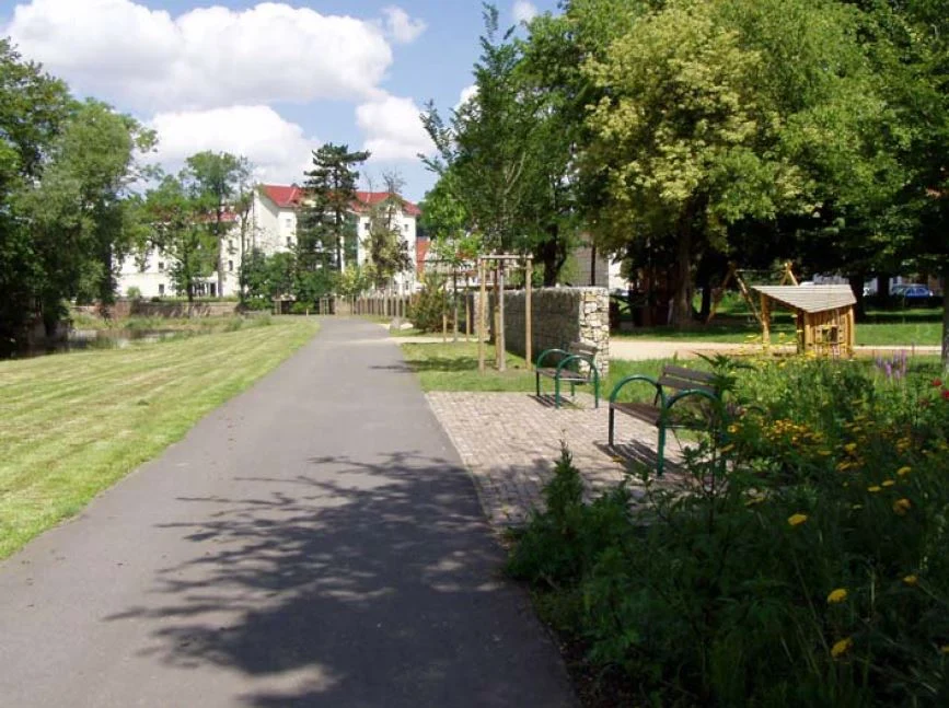 Blick auf einen asphaltierten Weg, umgeben von Grünanlagen