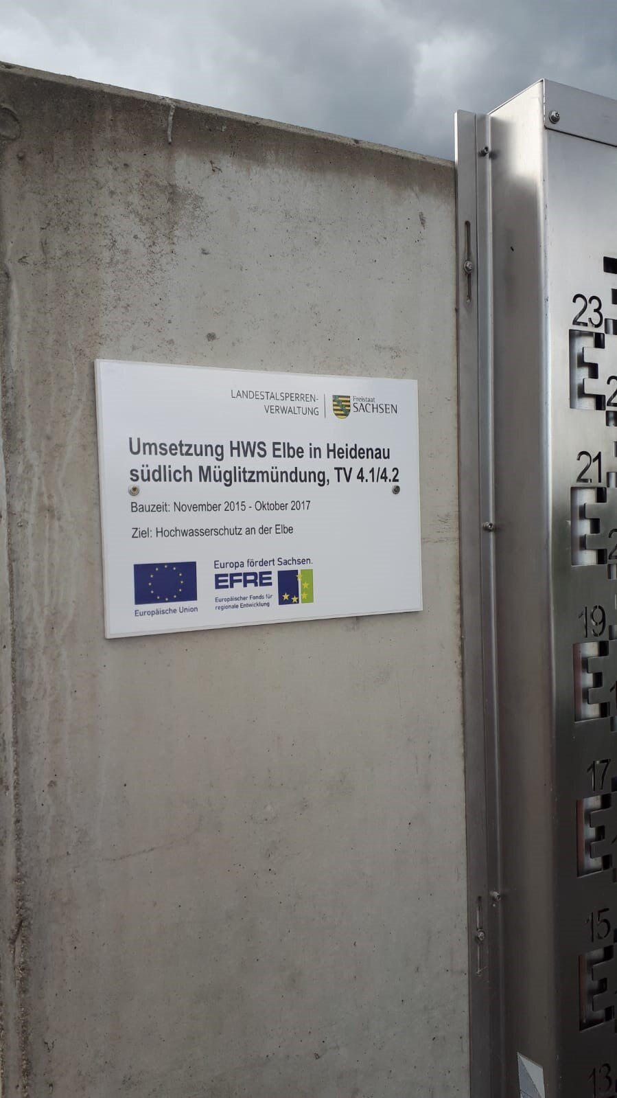 Ein Schild zum Projekt mit EU-Logos, angebracht auf einer Betonmauer