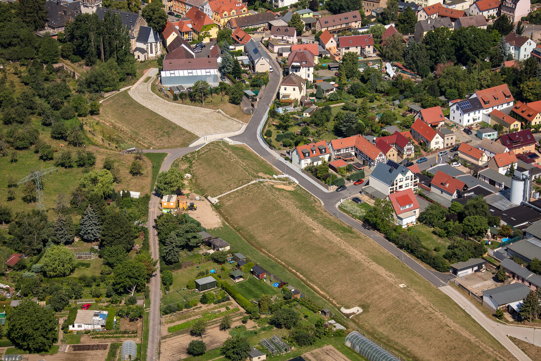 Blick aus der Luft auf einen Deich und einen Ort