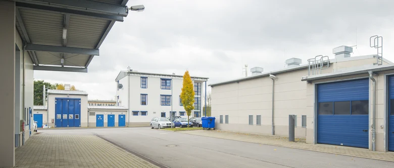ein Hof, umgeben von hellen Bürogebäuden mit blauen Fenstern und Toren