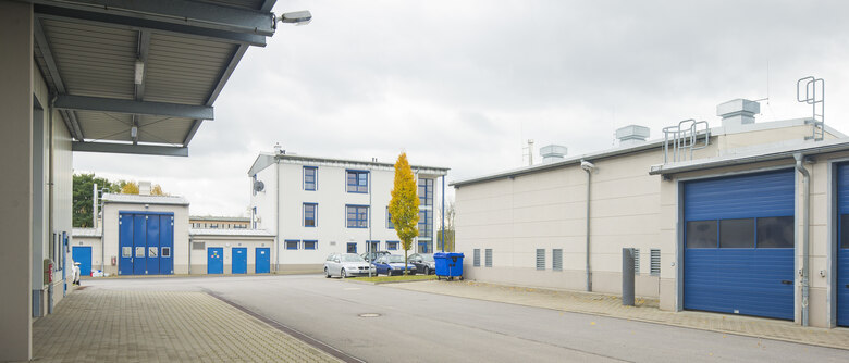 ein Hof, umgeben von hellen Bürogebäuden mit blauen Fenstern und Toren