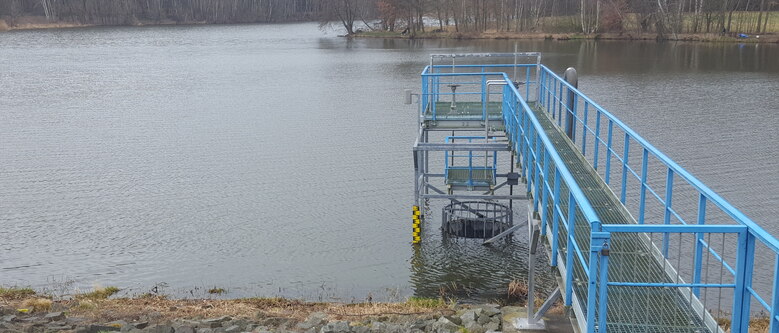 Blick auf einen blauen Bediensteg aus Metall der in einen See ragt