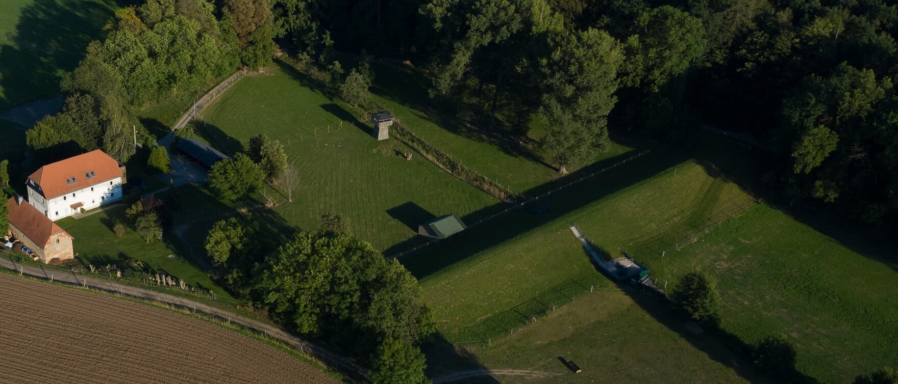 Luftbild vom Hochwasserrückhaltebecken umgeben von Wohnhäusern und Feldern