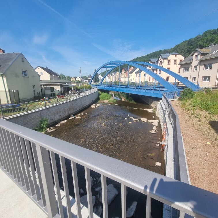 Blick von einer Brücke auf die nächste blaue Brücke über einen Fluss