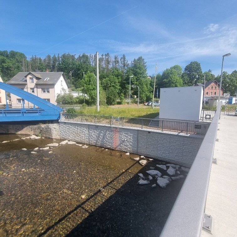 Blick von Brücke auf Fluss mit Mauer