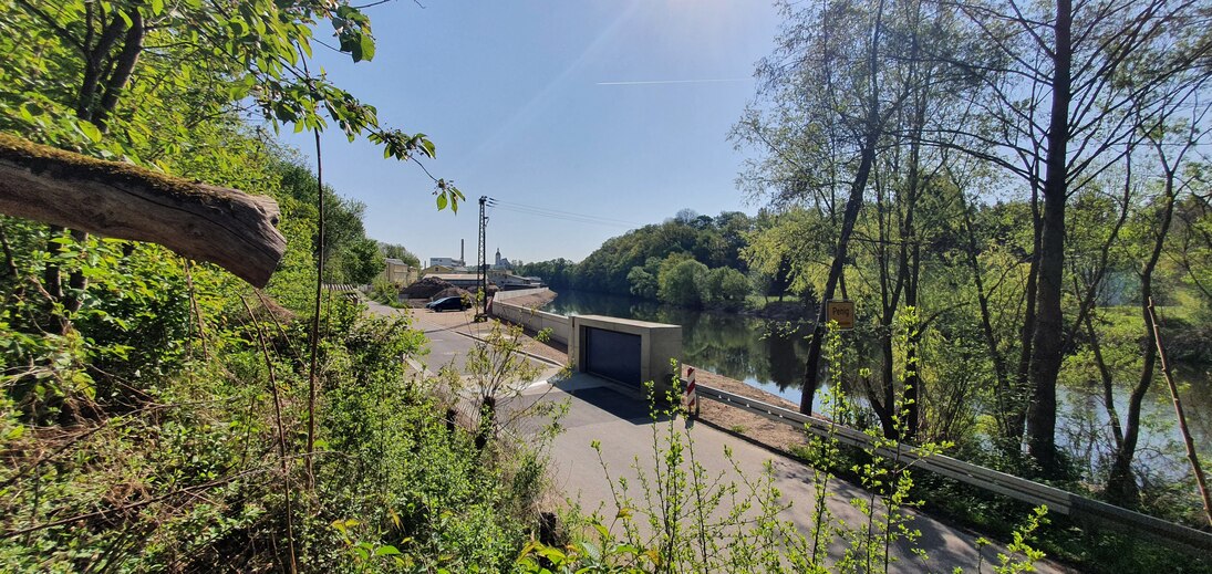 Blick aus dem Grünen auf eine Straße und einem Fluss dahinter