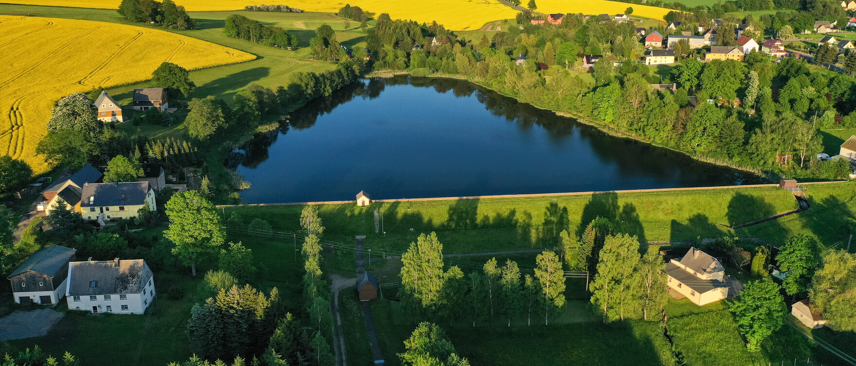 Luftbild von einem See umgeben von Wiesen und Feldern