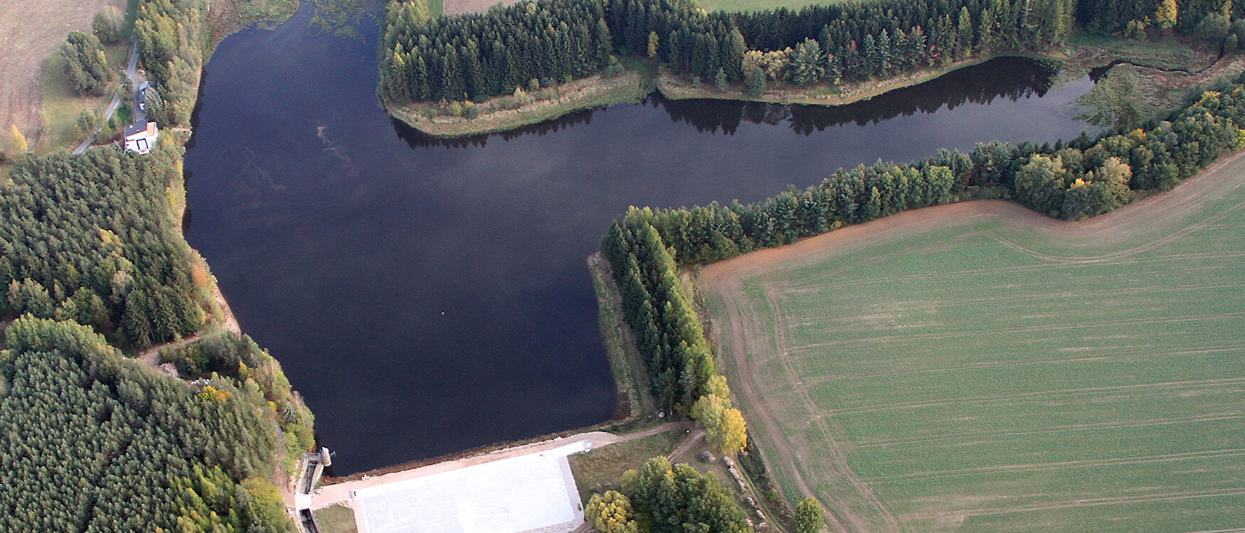 Luftbild eines Sees, umgeben von Wald und Feldern