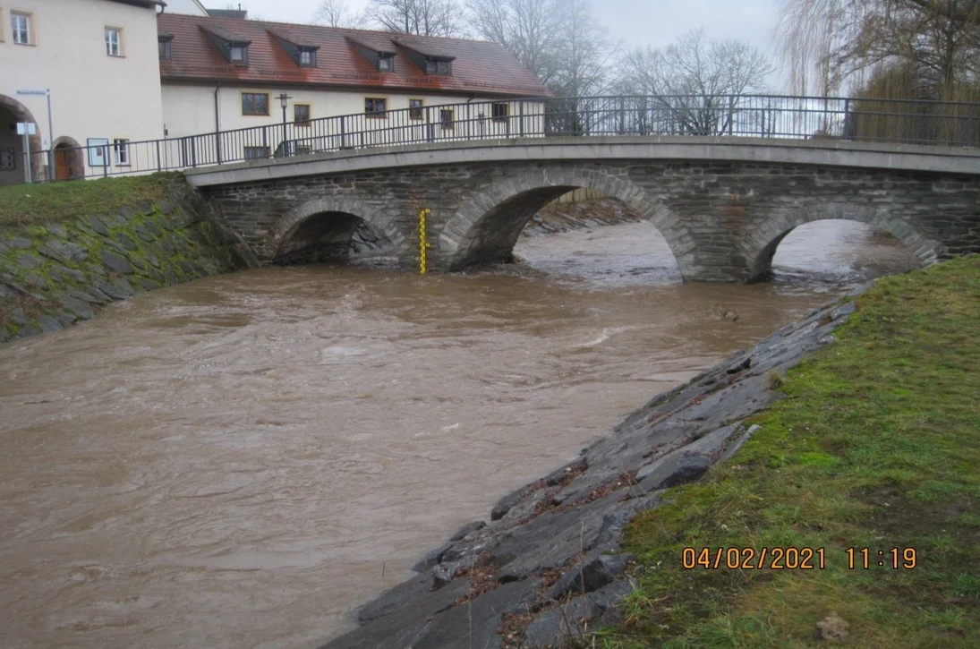 Blick auf einen Fluss über den eine steinerne Brücke führt