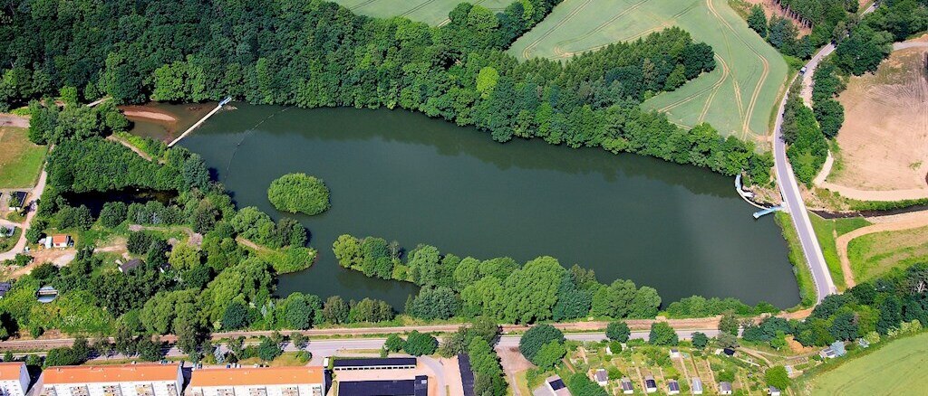 Luftbild eines Sees neben Häusern und umgeben von Grün