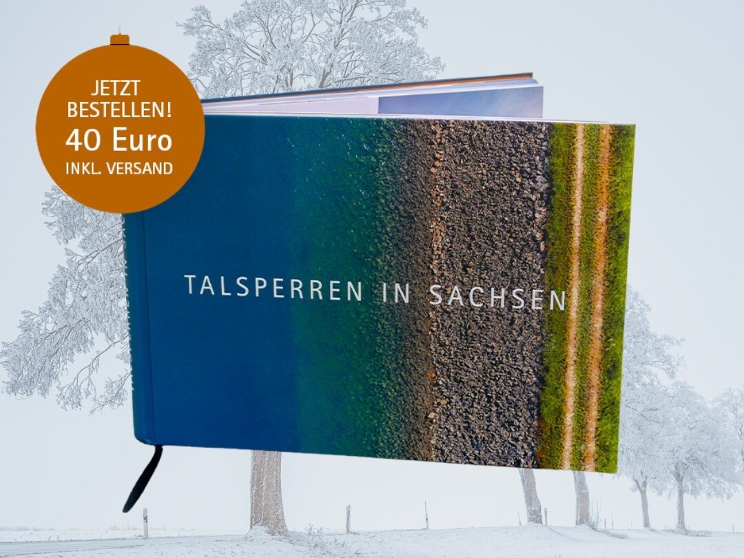 Das Talsperrenbuch liegt am Strand umringt von Kieselsteinen